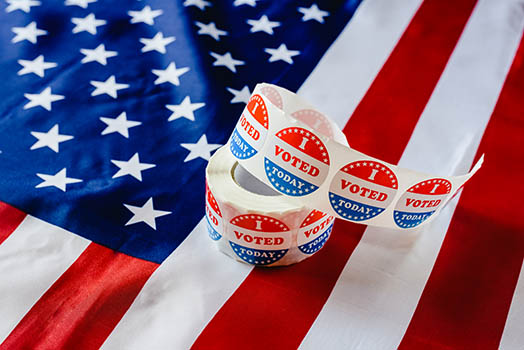 roll of "i voted" stickers on top of American flag
